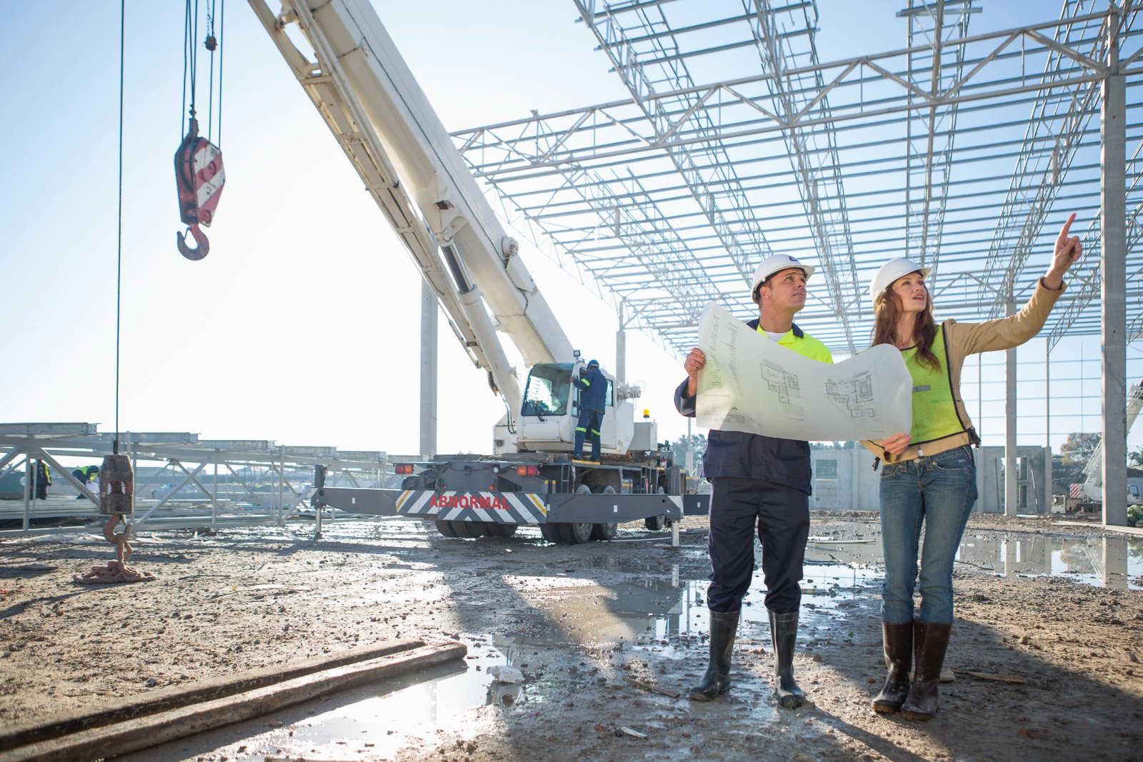 Ingenieros revisando planos durante el montaje estructural de una nave industrial.