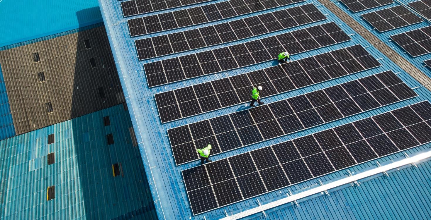 Instalación de paneles solares en cubierta industrial con técnicos realizando mantenimiento.