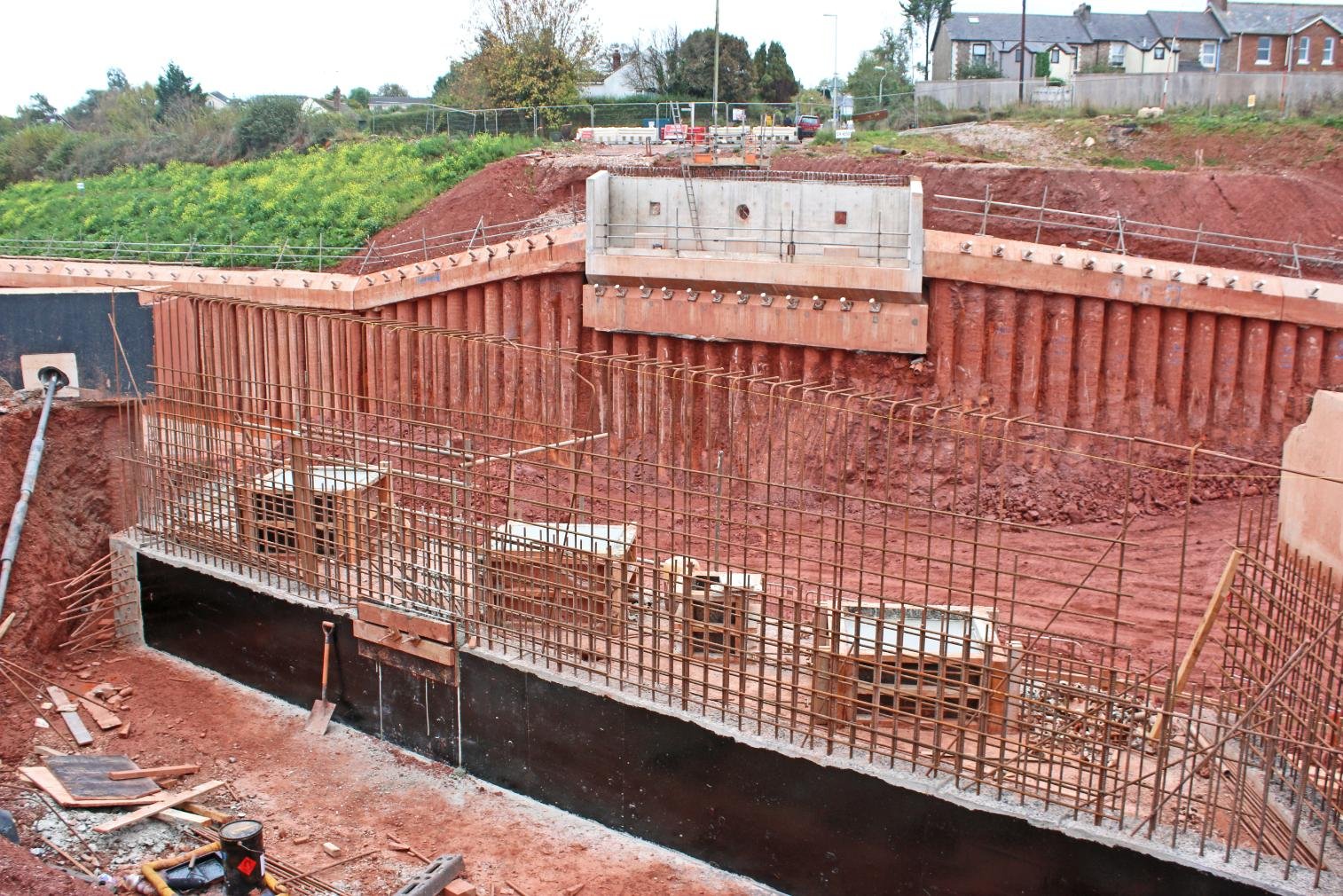 Muro de contención de hormigón armado en fase de construcción con armaduras y encofrado.