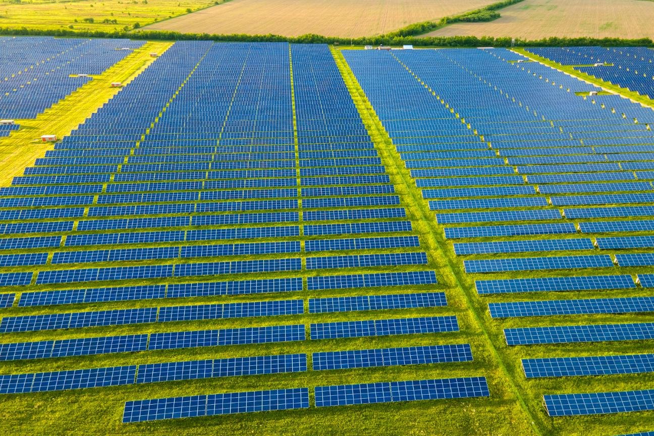 Vista aérea de planta fotovoltaica con paneles solares instalados en suelo sobre terreno verde.