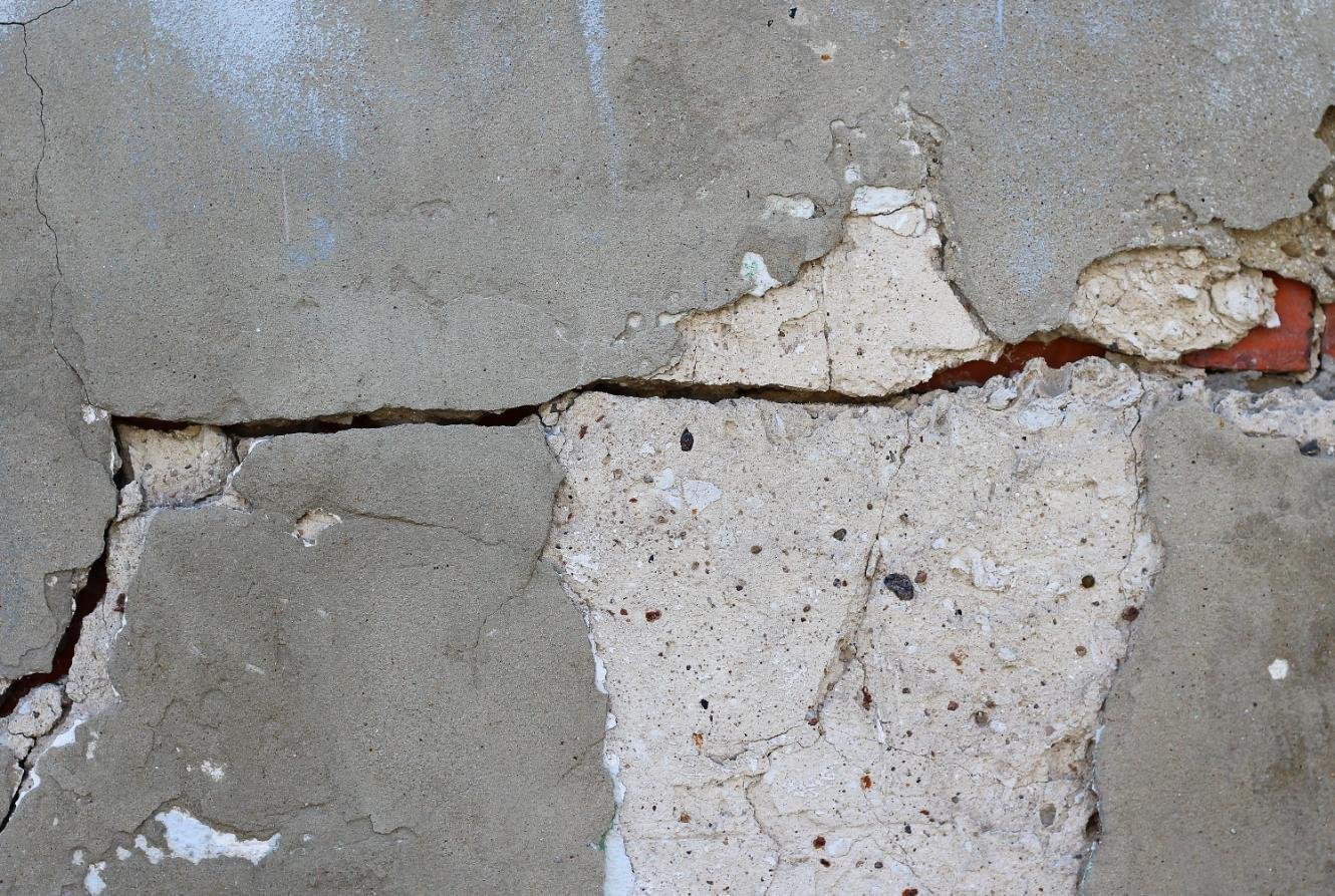 Fisura en muro de hormigón con desprendimiento del revestimiento, utilizada para ilustrar patologías estructurales y necesidad de refuerzos en edificaciones.